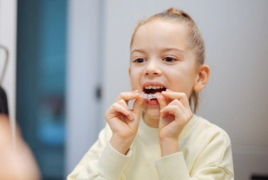 Smiling man placing an Invisalign clear aligner in his mouth, Precision Dental Care, Imperial, MO