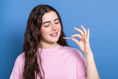 Smiling teen girl holding an Invisalign clear aligner, Precision Dental Care, Imperial, MO