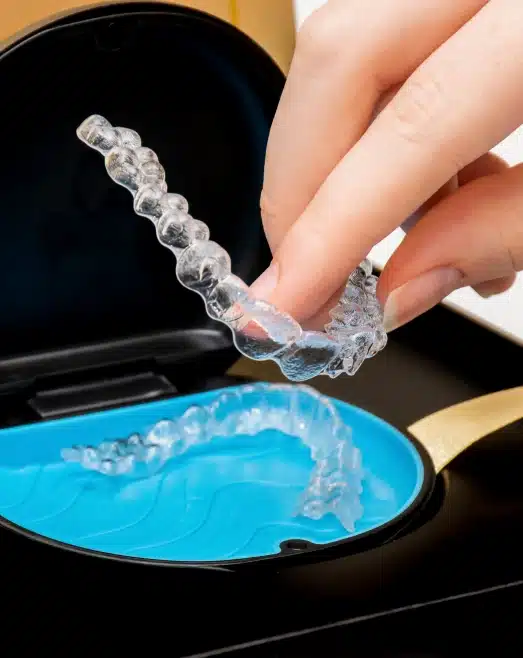 Hand holding a clear aligner over its storage case, Precision Dental Care, Imperial, MO